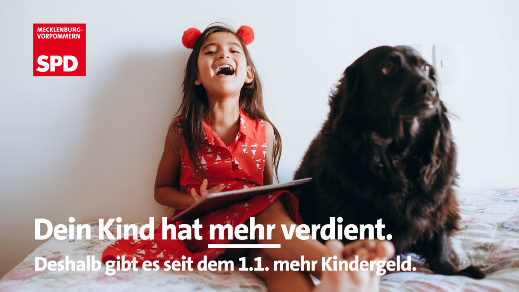 Zu sehen ist ein lachendes Kind im roten Kleid, neben der ein schwarzer Hund sitzt. Darüber ist ein weißer Schrift zu lesen: Dein Kind hat mehr verdient. Deshalb gibt es seit dem 1.1. mehr Kindergeld.
