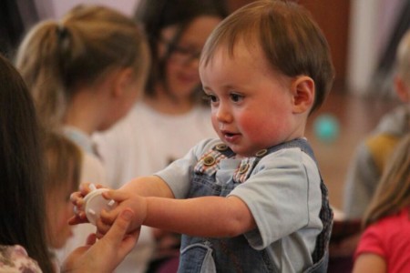 Ein Kind einer Kindergartengruppe übergibt einem anderen Kind ein Spielzeug.