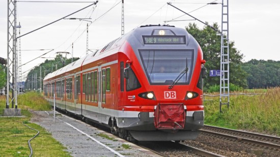 Ein Zug der Linie RE 9 nach Rostock Hauptbahnhof auf den Gleisen in freiem Feld.